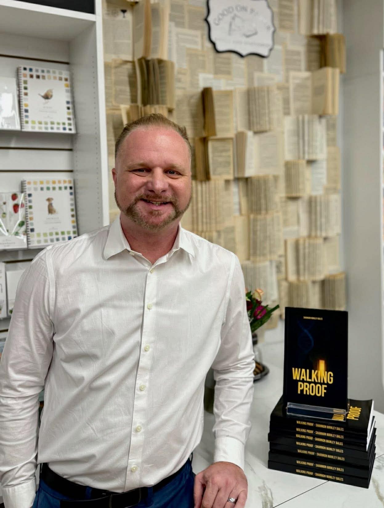 Shannon Manley Bales smiling beside a stack of Walking Proof books at a bookstore signing